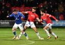 Oldham Athletic's Zak Dearnley tries to escape Jordan Turnbull and Jason Lowe of Salford City