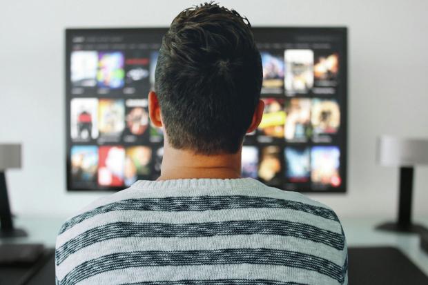 The Oldham Times: A man watching a smart TV. Credit: Canva