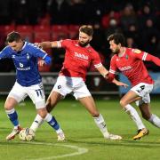Oldham Athletic's Zak Dearnley tries to escape Jordan Turnbull and Jason Lowe of Salford City