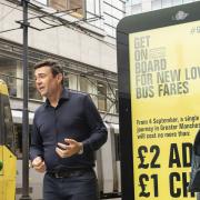 Andy Burnham and Amanda Chadderton stand in front of a Manchester digital advertising board announcing the fare slash