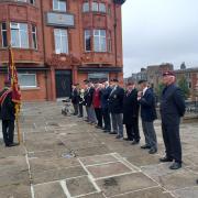 Veterans stand opposite the war memorial facing the standards