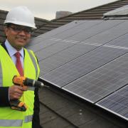 Cllr Abdul Jabbar in 2016, standing next to the newly installed solar panels